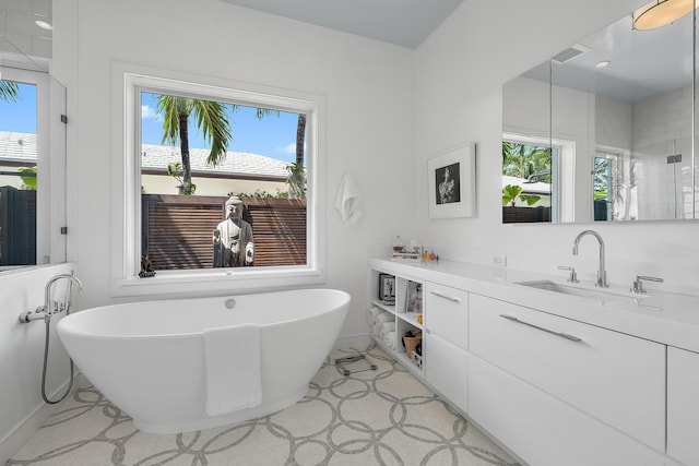 bathroom with a tub to relax in, vanity, and a healthy amount of sunlight