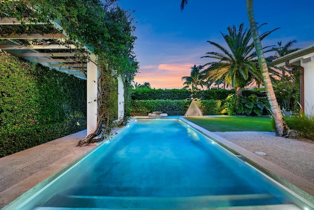 pool at dusk featuring a lawn