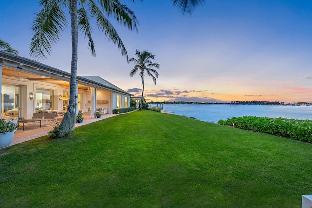 yard at dusk featuring a water view