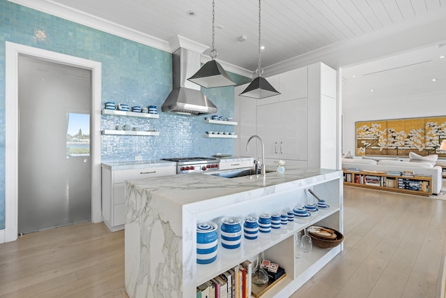 kitchen with pendant lighting, sink, white cabinetry, and wall chimney exhaust hood