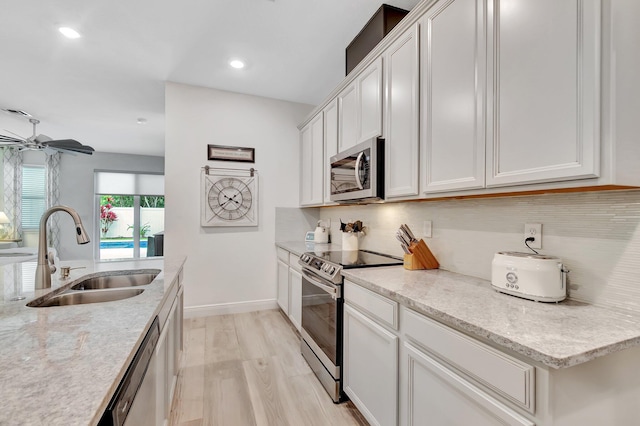 kitchen featuring backsplash, appliances with stainless steel finishes, a sink, and light wood-type flooring