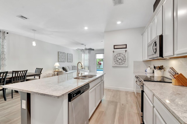 kitchen with visible vents, ceiling fan, a sink, light wood finished floors, and stainless steel appliances