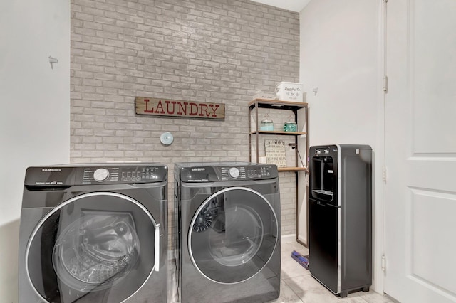 laundry room with separate washer and dryer, laundry area, and brick wall