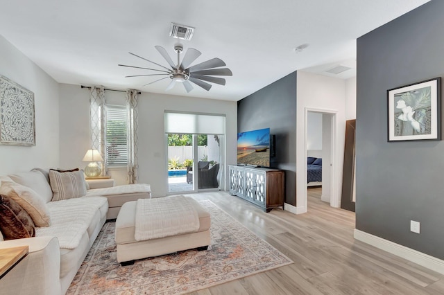 living area with visible vents, light wood finished floors, ceiling fan, and baseboards