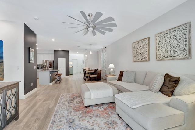 living room featuring recessed lighting, light wood-style flooring, ceiling fan, and baseboards