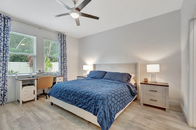 bedroom featuring baseboards, a ceiling fan, and light wood-style flooring