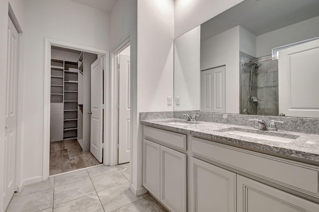 full bath with double vanity, a walk in closet, a sink, and a stall shower