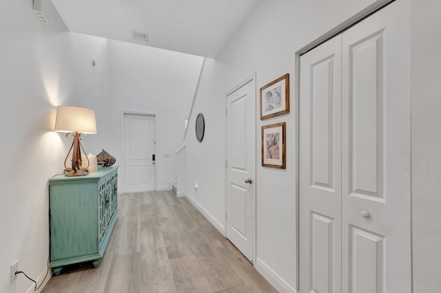 corridor with visible vents, light wood-style flooring, and baseboards