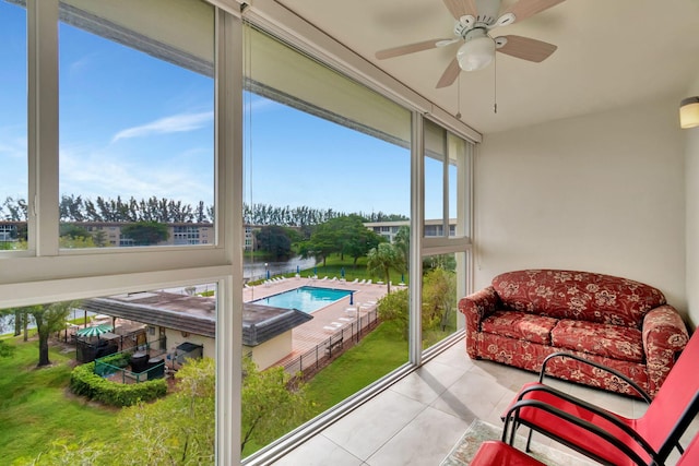 sunroom featuring ceiling fan and a water view