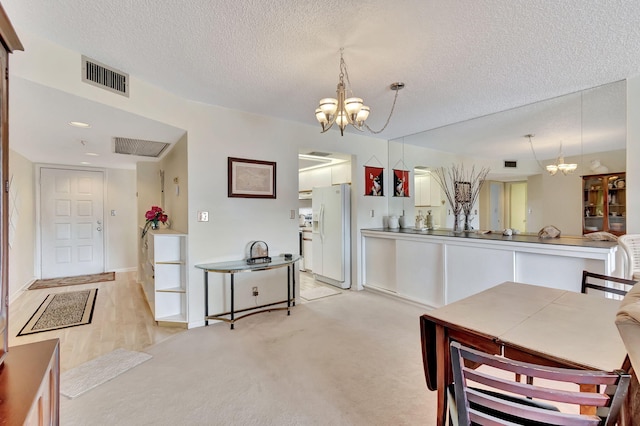 carpeted dining space featuring a textured ceiling and a notable chandelier