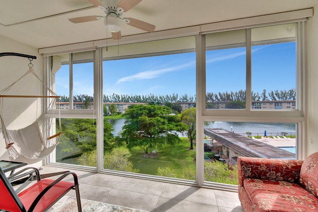 sunroom / solarium featuring a water view and ceiling fan