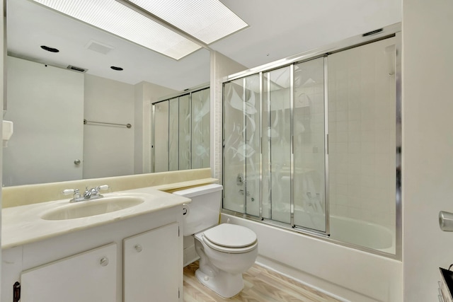 full bathroom featuring bath / shower combo with glass door, vanity, wood-type flooring, and toilet