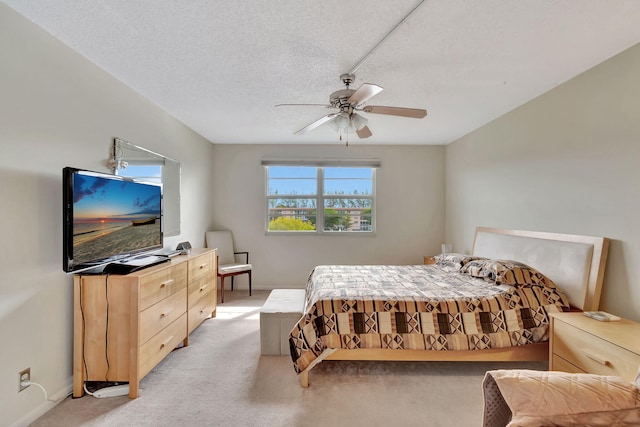 carpeted bedroom featuring ceiling fan and a textured ceiling