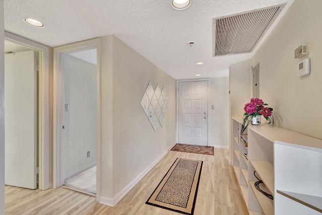 entrance foyer with a textured ceiling and light hardwood / wood-style flooring