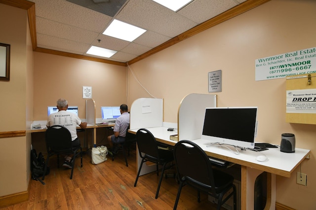 office area featuring hardwood / wood-style floors, a drop ceiling, and ornamental molding