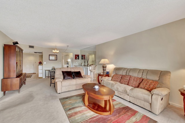 carpeted living room with a textured ceiling and an inviting chandelier