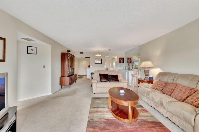 carpeted living room featuring a chandelier and a textured ceiling