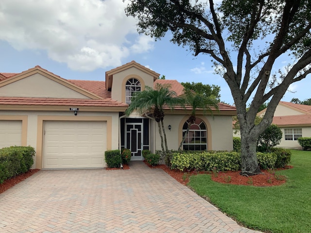 mediterranean / spanish-style home featuring a front lawn and a garage