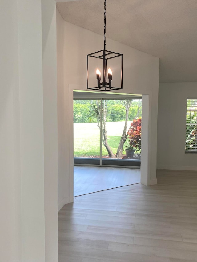 unfurnished dining area featuring light wood-type flooring and an inviting chandelier