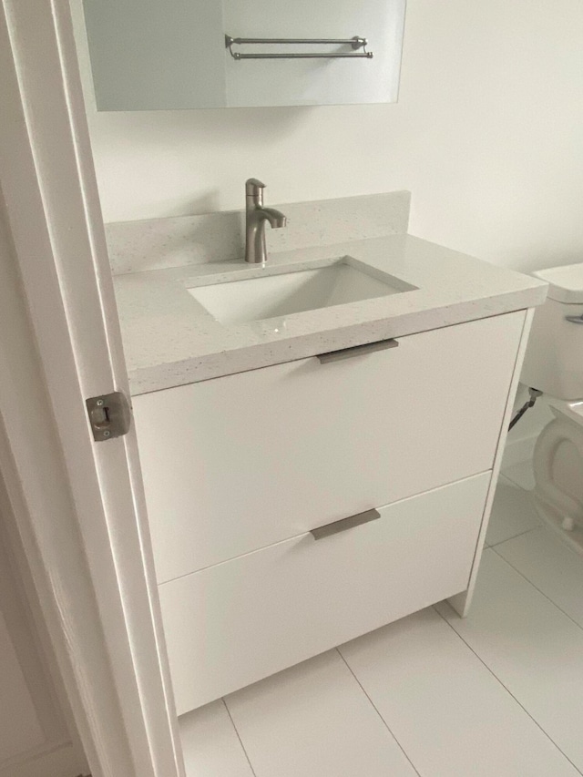 bathroom with tile patterned flooring, vanity, and toilet