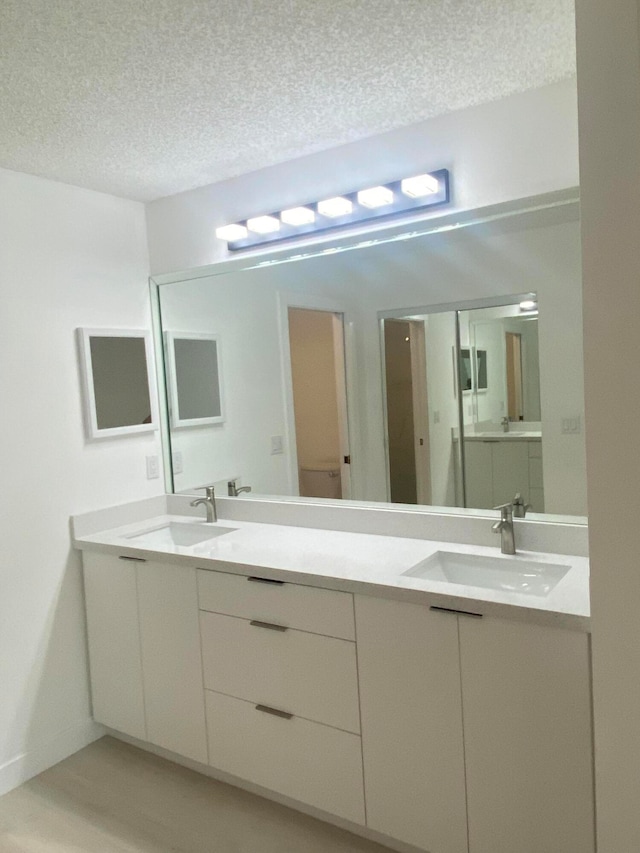 bathroom featuring hardwood / wood-style floors, vanity, and a textured ceiling