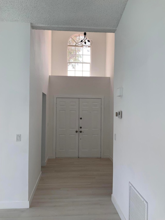 foyer entrance featuring light hardwood / wood-style floors, an inviting chandelier, and a textured ceiling