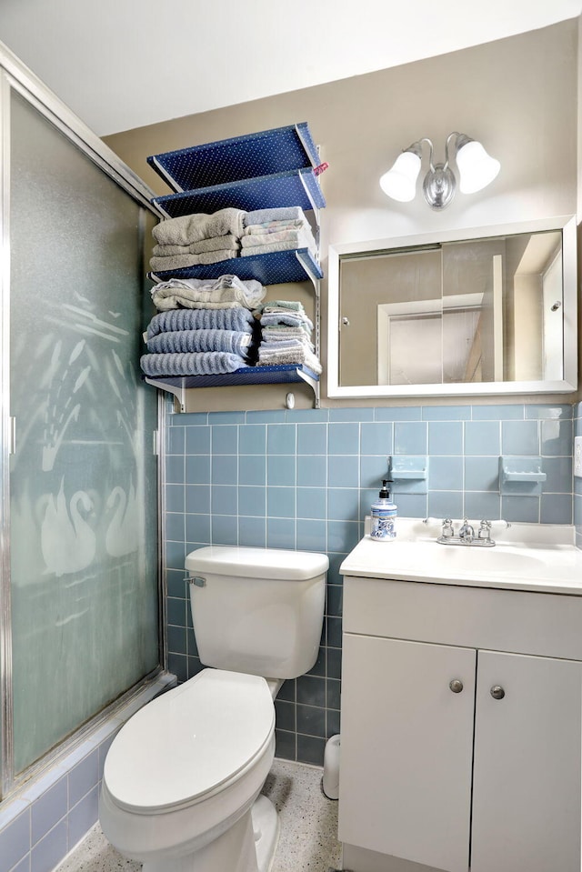 bathroom featuring vanity, tile walls, toilet, and a shower with door