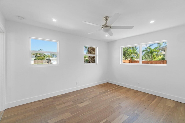 empty room featuring ceiling fan, light wood-type flooring, and a wealth of natural light