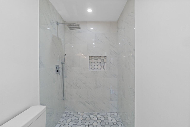 bathroom featuring a tile shower and toilet