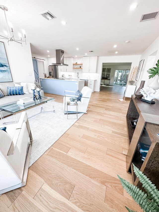 living room with a notable chandelier, sink, and light hardwood / wood-style floors