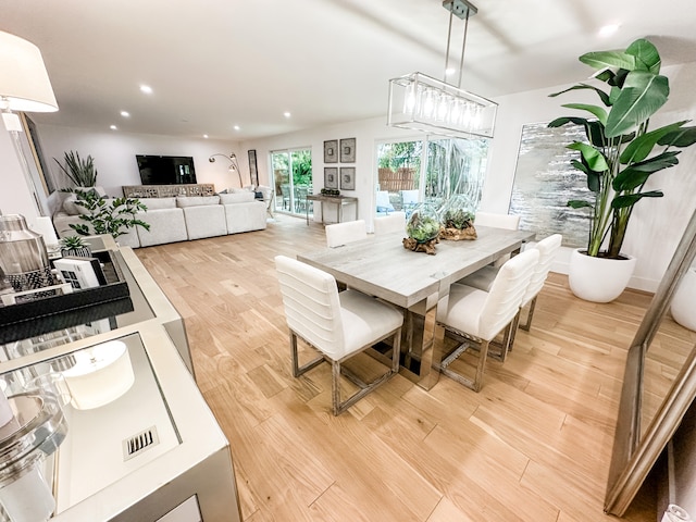 dining space with a notable chandelier and light hardwood / wood-style flooring