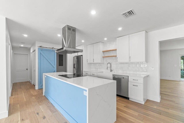 kitchen with light hardwood / wood-style floors, island range hood, appliances with stainless steel finishes, a center island, and white cabinetry