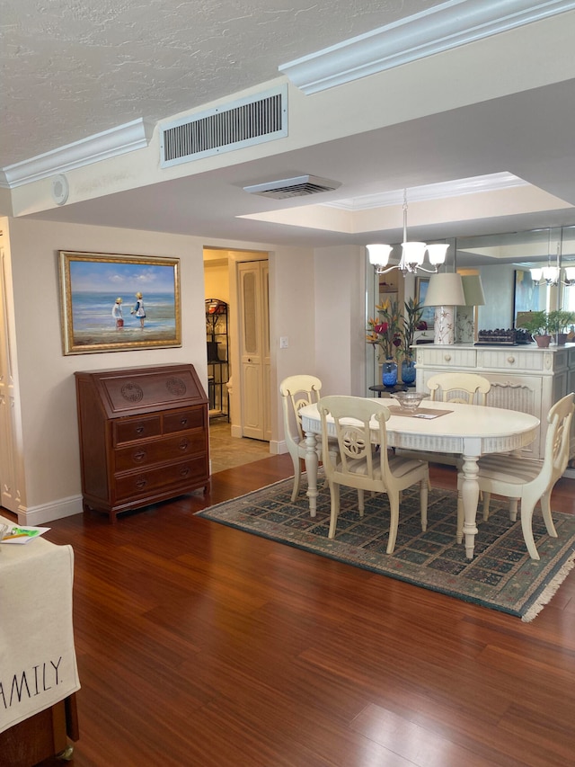 dining space with dark wood-type flooring, crown molding, a textured ceiling, and a chandelier