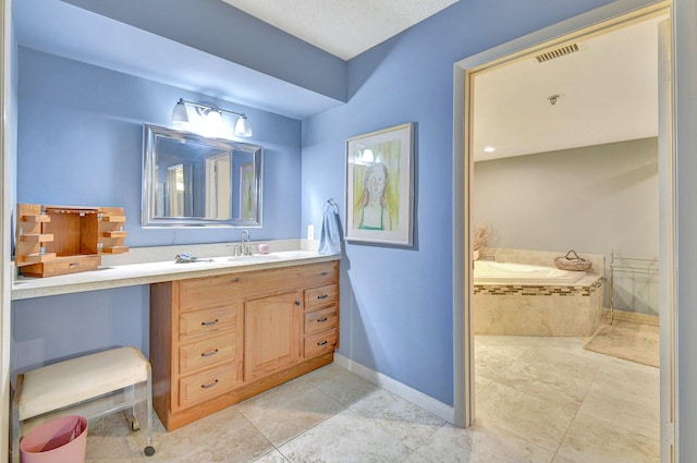 bathroom with vanity, a textured ceiling, tile patterned floors, and tiled bath