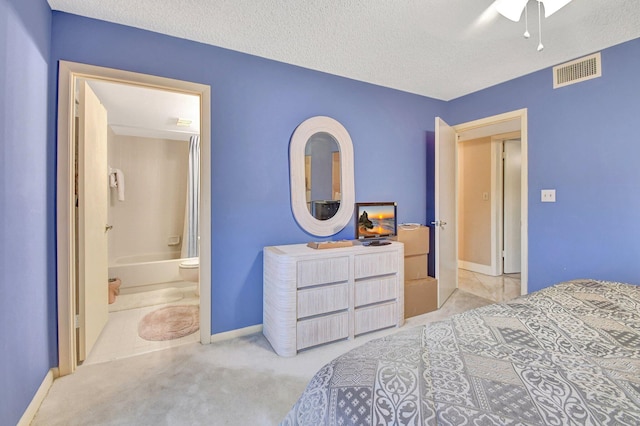 bedroom with connected bathroom, light carpet, a textured ceiling, and ceiling fan