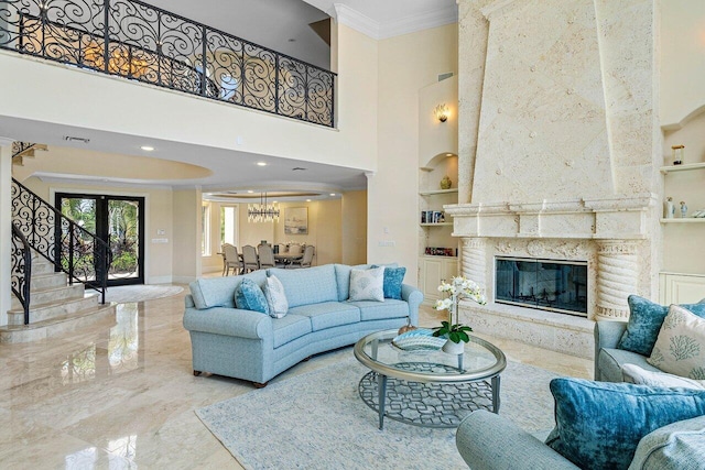 living room featuring a towering ceiling, a premium fireplace, ornamental molding, and built in features