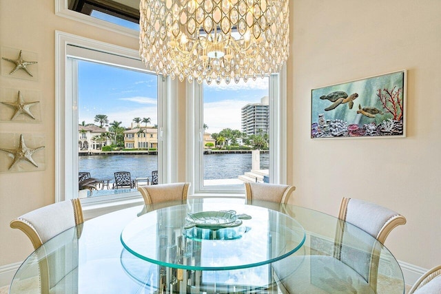 dining space featuring a water view, an inviting chandelier, and plenty of natural light