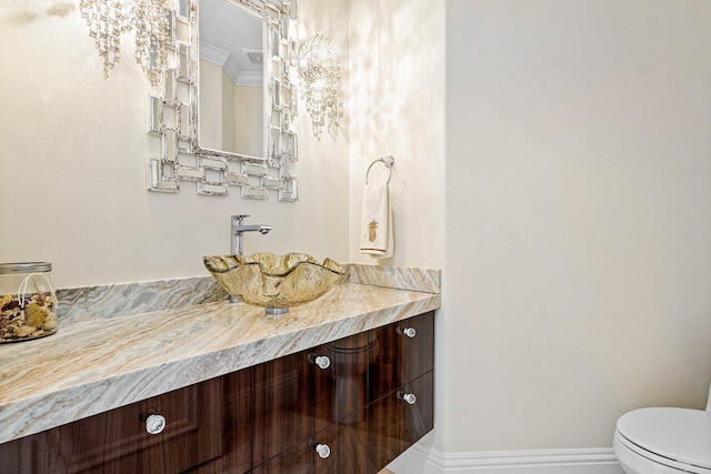 bathroom featuring vanity, crown molding, and toilet