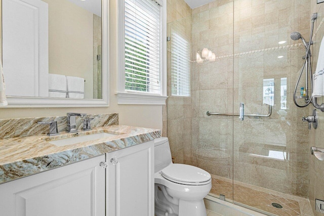 bathroom featuring toilet, vanity, and a shower with door