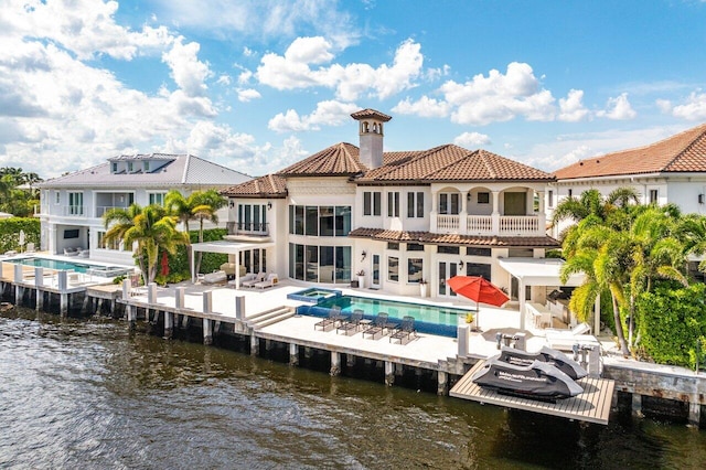 back of house with a water view, a patio area, and a balcony