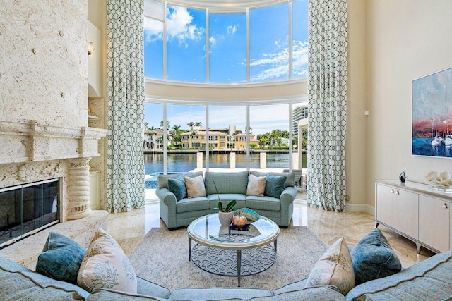 living room featuring a water view, a fireplace, and a high ceiling