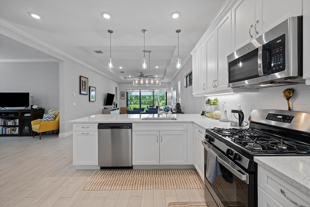 kitchen with stainless steel appliances, kitchen peninsula, sink, and white cabinets