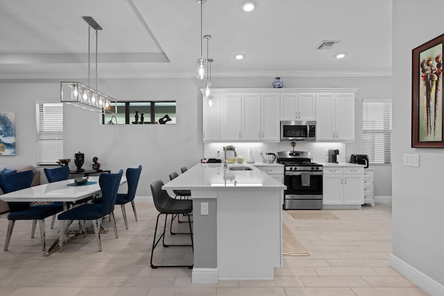 kitchen featuring pendant lighting, a kitchen island with sink, stainless steel appliances, and white cabinets