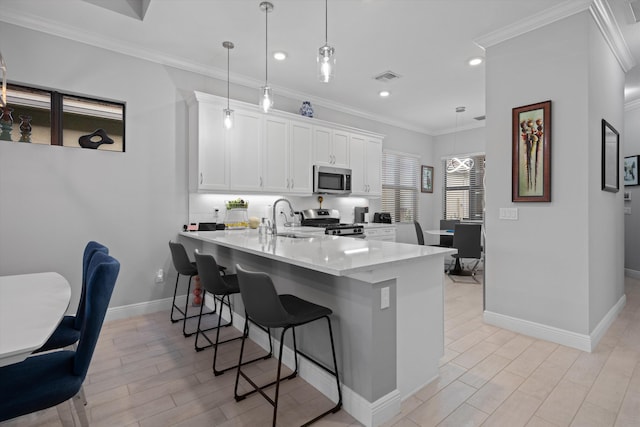 kitchen with white cabinets, pendant lighting, sink, stainless steel appliances, and a breakfast bar