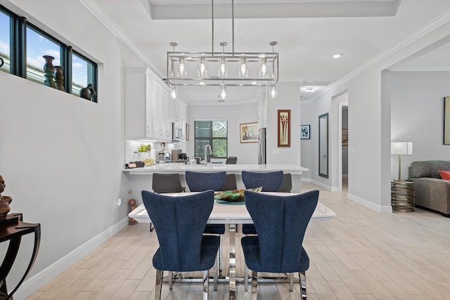 dining space with ornamental molding, sink, and light hardwood / wood-style floors