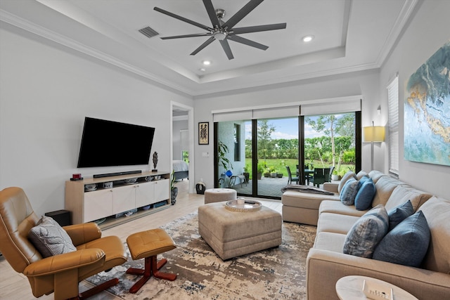 living room with hardwood / wood-style flooring, crown molding, ceiling fan, and a tray ceiling