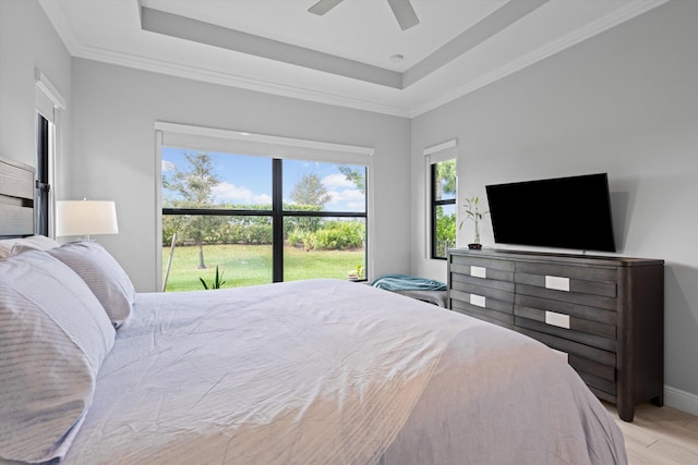 bedroom featuring ceiling fan, a tray ceiling, crown molding, and light hardwood / wood-style floors