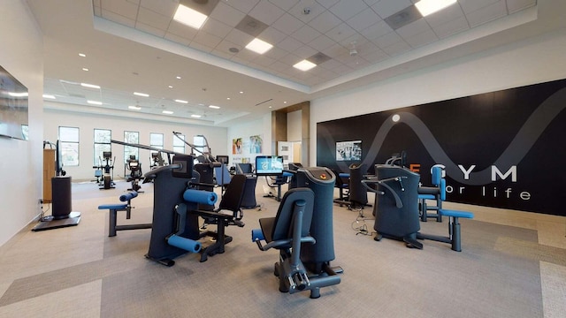 gym featuring a paneled ceiling, light carpet, and a tray ceiling