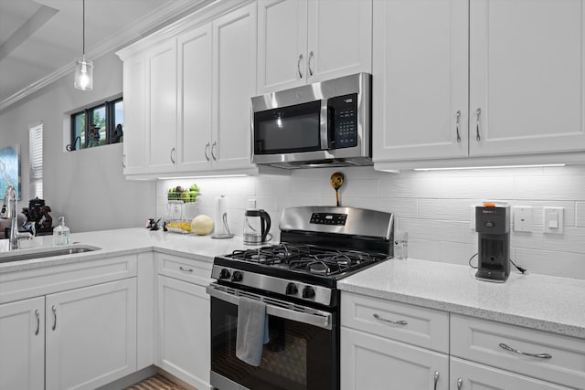 kitchen with crown molding, decorative light fixtures, sink, appliances with stainless steel finishes, and white cabinetry