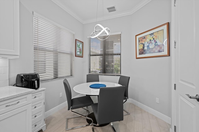 dining area with crown molding, a chandelier, and light hardwood / wood-style floors